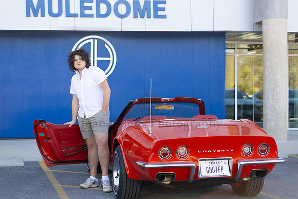 Alamo Heights HS Senior with convertible red corvette the the Alamo Heights Muledome stadium